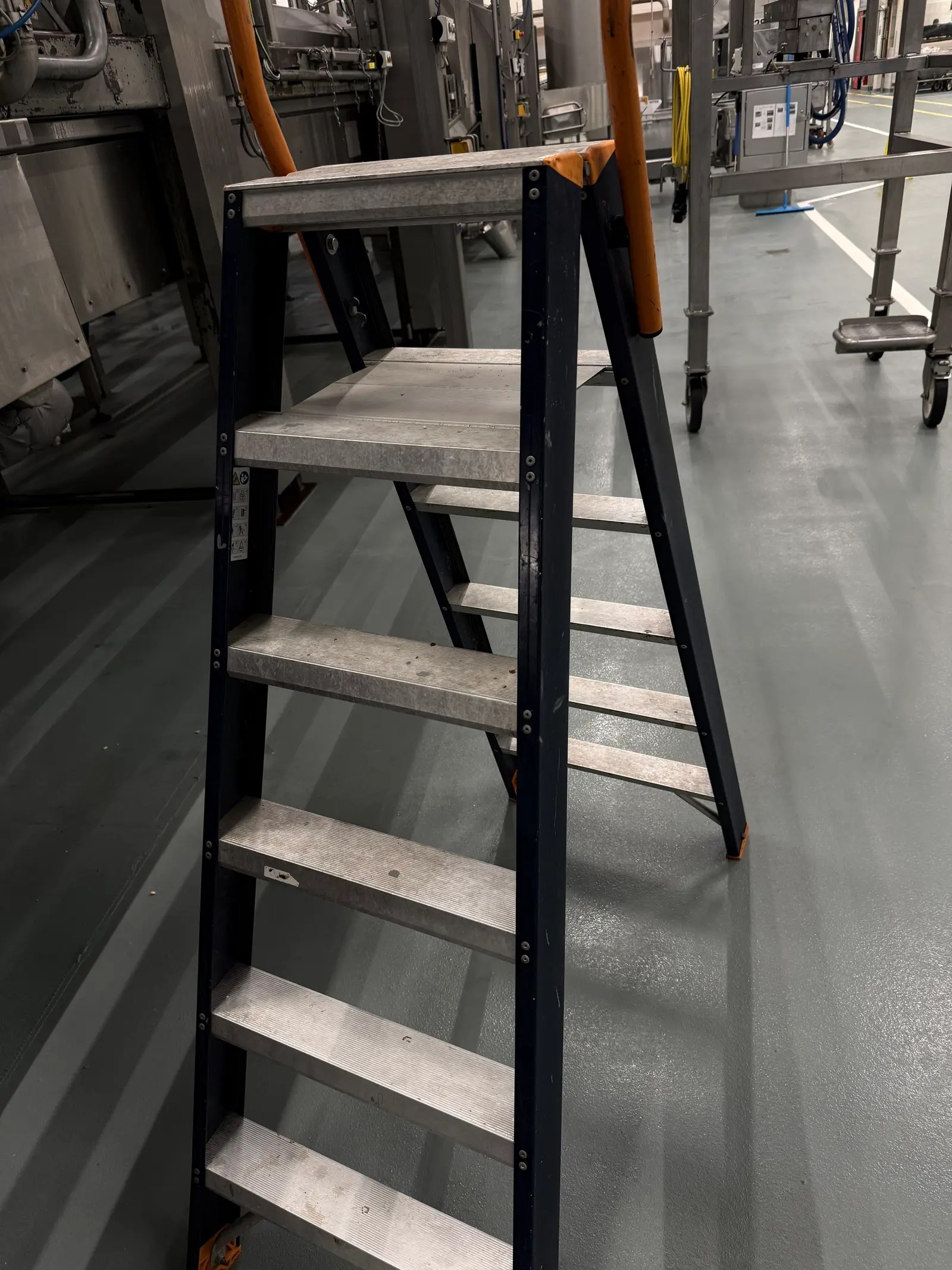 Stalen trapladder met platform op een industriële werkvloer